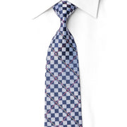 A patterned necktie with a blue, white, and gray geometric design, styled on a white collared dress shirt against a white background.