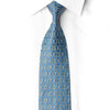 Full-length diagonal view of a blue silk tie featuring a gold-toned geometric lattice and scattered teal and iridescent crystal rhinestones.