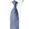 San-Dee steel blue floral arabesque rhinestone silk necktie worn with white dress shirt, showing diagonal navy stripe bands with crystal silver sparkle